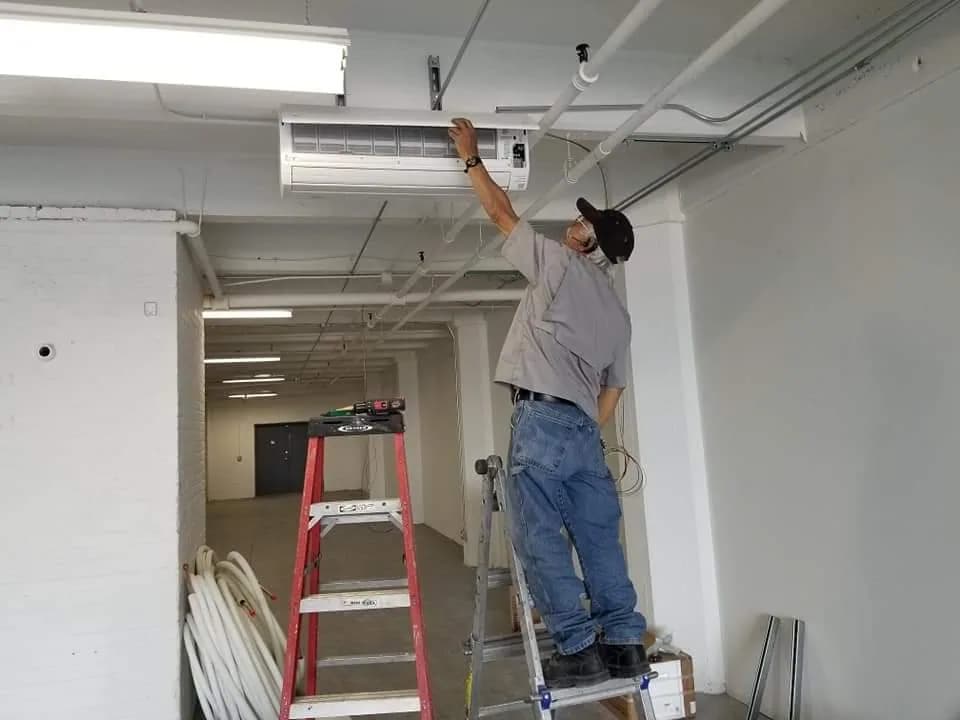 Ventilation System Installation Chicago — technician installing a commercial ceiling-mounted HVAC unit