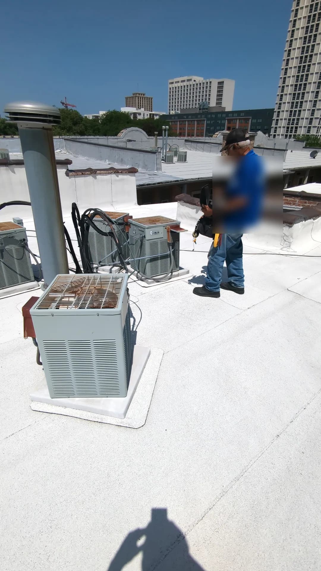 Central Air Conditioner Installation — technician inspecting multiple commercial rooftop air-conditioning units