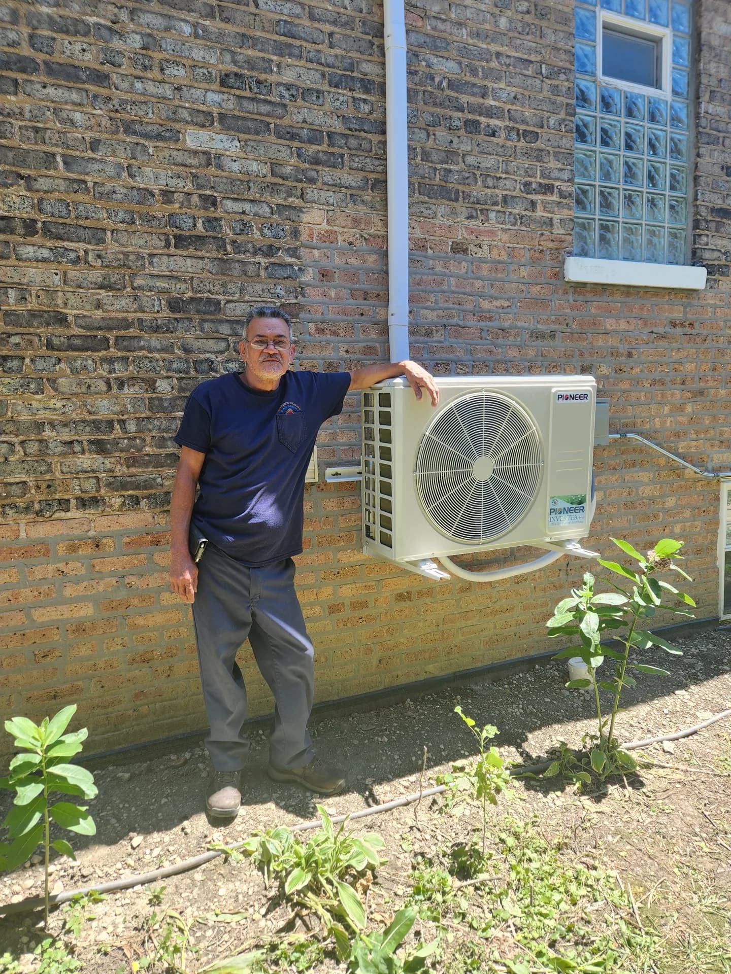 HEPA Filtration Systems Chicago — Bernie's technician standing beside a ductless mini-split outdoor unit
