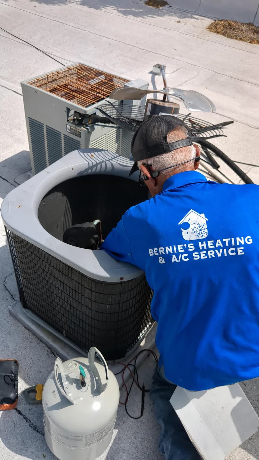 Bernie's technician servicing an open rooftop air-conditioning condenser