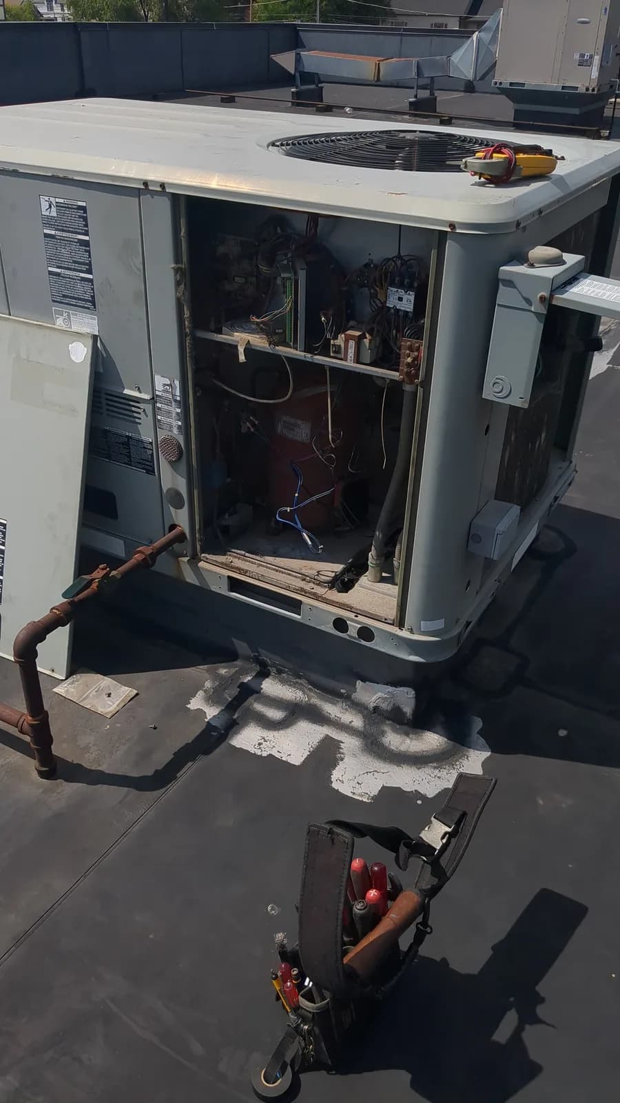Open commercial rooftop packaged HVAC unit with service tools
